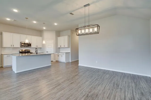 a view of kitchen with granite countertop cabinets and refrigerator