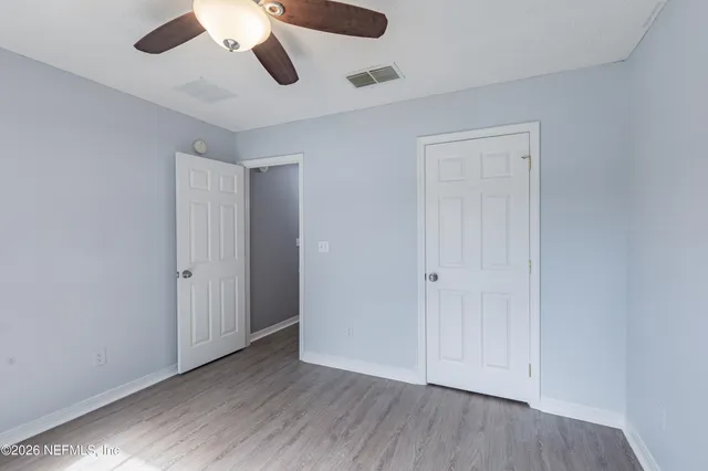an empty room with wooden floor ceiling fan and windows