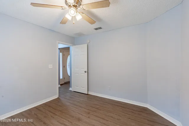 a view of an empty room and wooden floor chandelier fan