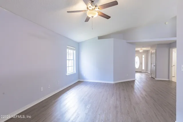 a view of an empty room with window and wooden floor