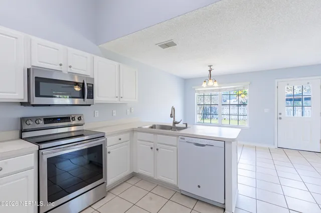 a kitchen with granite countertop white cabinets stainless steel appliances and a window
