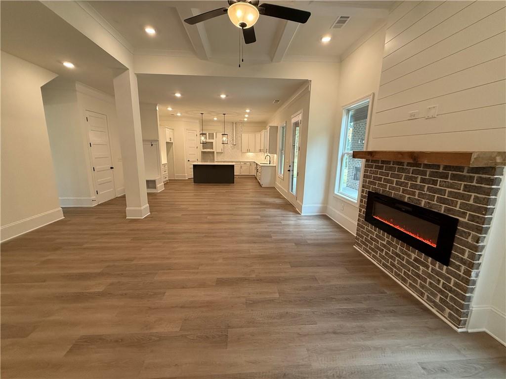 3229 Traditions Way Jefferson, GA 30549 - Photo 11 of 43 a view of an empty room and kitchen with ceiling fan wooden floor and a ceiling fan
