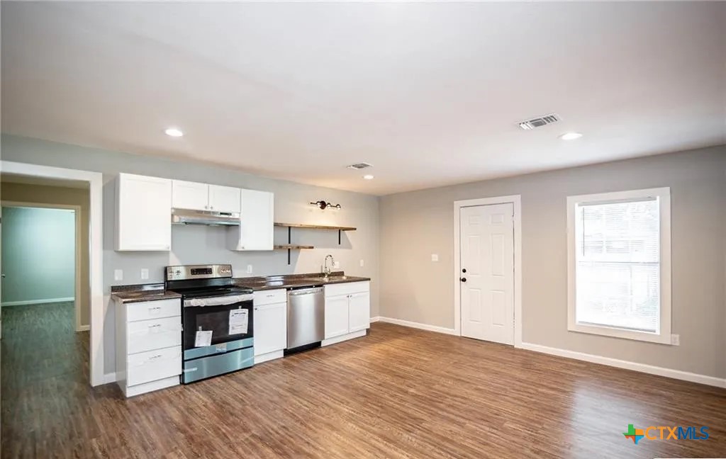 2003 Woodlawn Street Victoria, TX 77901 - Photo 7 of 35 a kitchen with stainless steel appliances granite countertop a stove top oven a sink dishwasher and a refrigerator with wooden floor