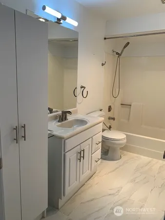 a bathroom with a granite countertop sink a toilet and shower