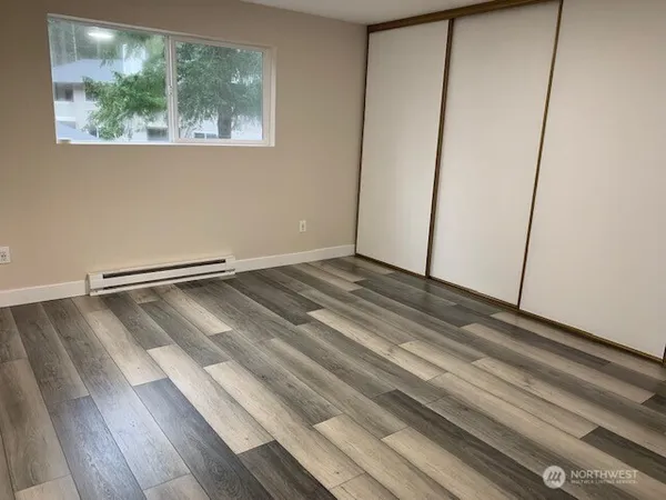 a view of an empty room with wooden floor and a window