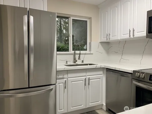a kitchen with stainless steel appliances granite countertop a refrigerator and a sink