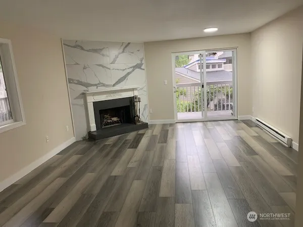 an empty room with wooden floor fireplace and windows