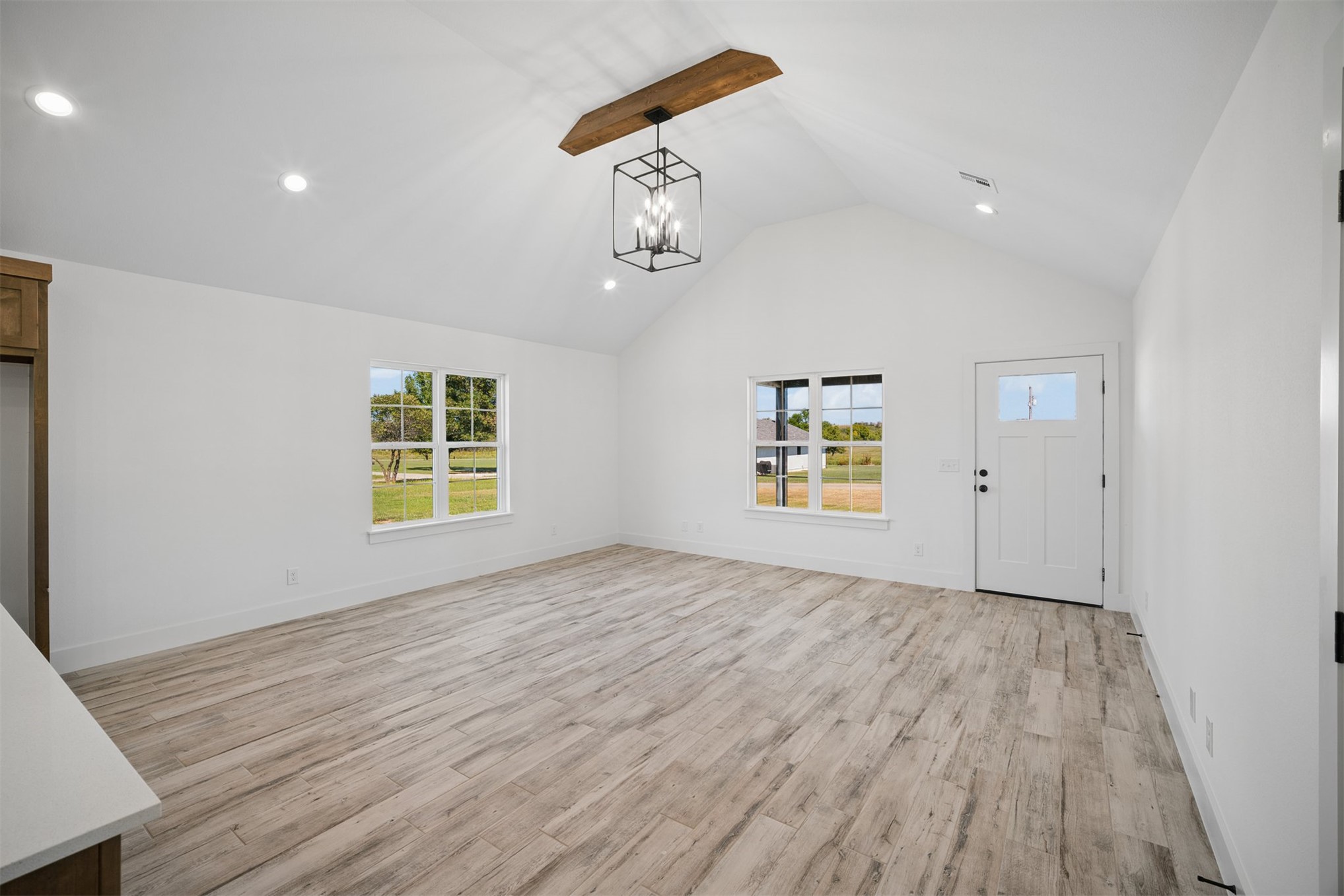 25036 South 4205 Road Inola, OK 74036 - Photo 4 of 30 Vaulted ceiling with exposed wood beam, recessed lighting, wood-finish flooring, white paneled door with glass insert, and multiple windows providing natural light