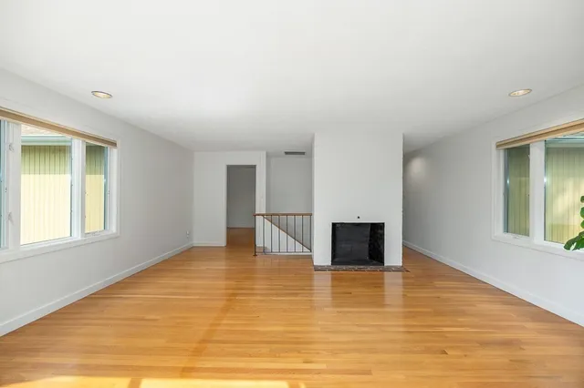a view of empty room with wooden floor and fireplace