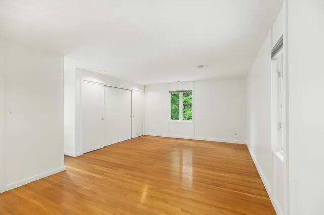 a view of empty room with wooden floor
