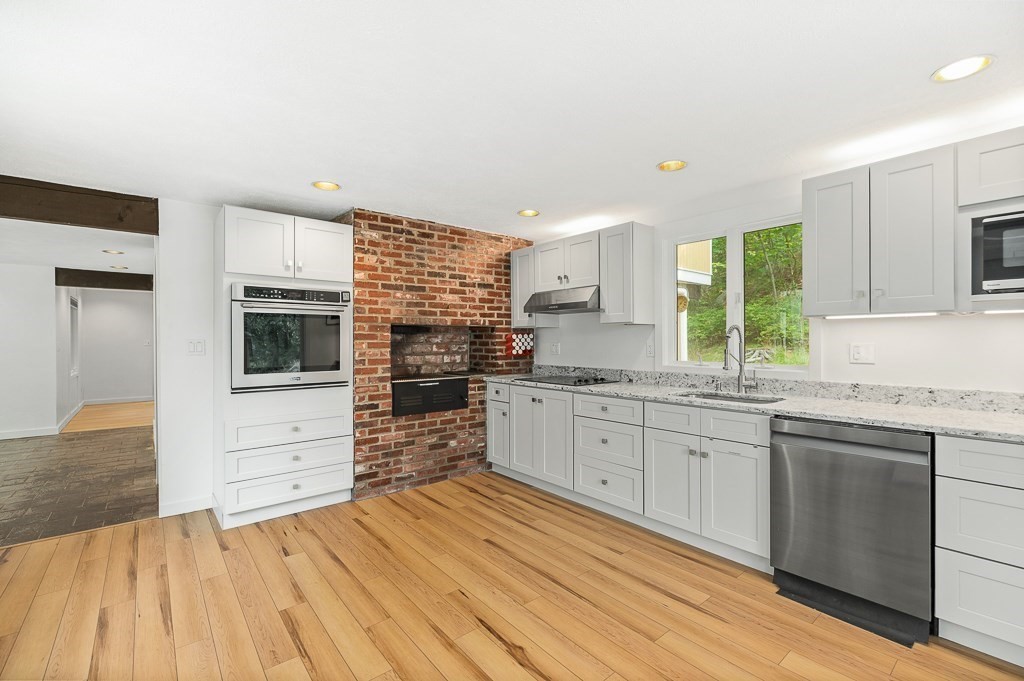2 Moses Hill Road Manchester, MA 01944 - Photo 7 of 30 a kitchen with stainless steel appliances kitchen island granite countertop a stove top oven a sink with cabinets and wooden floor