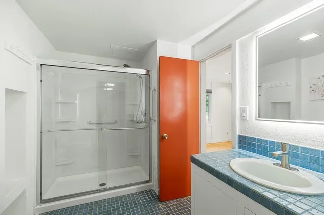 a bathroom with a granite countertop shower sink and mirror