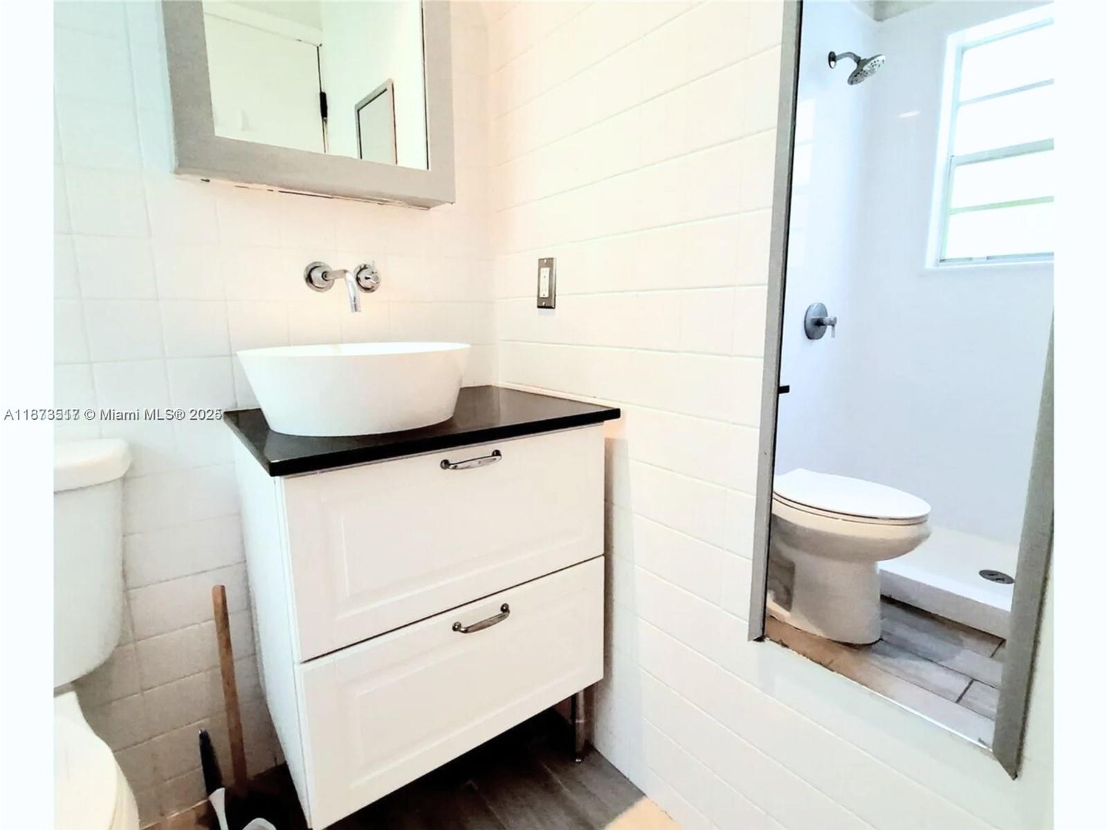 1009 Meridian Avenue, Unit 13 Miami Beach, FL 33139 - Photo 15 of 17 a bathroom with a toilet a sink and a mirror