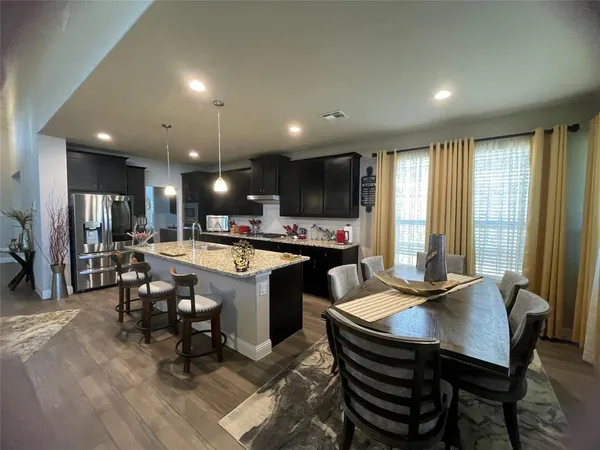 a kitchen with a dining table chairs and refrigerator
