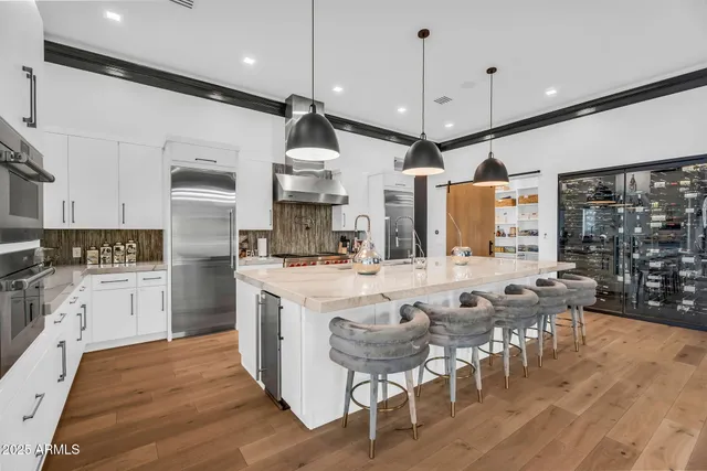 a kitchen with stainless steel appliances kitchen island granite countertop a stove a sink a dining table and chairs with wooden floor