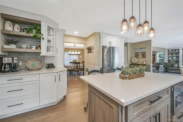 a kitchen with stainless steel appliances granite countertop a refrigerator a sink a stove and white cabinets with wooden floor