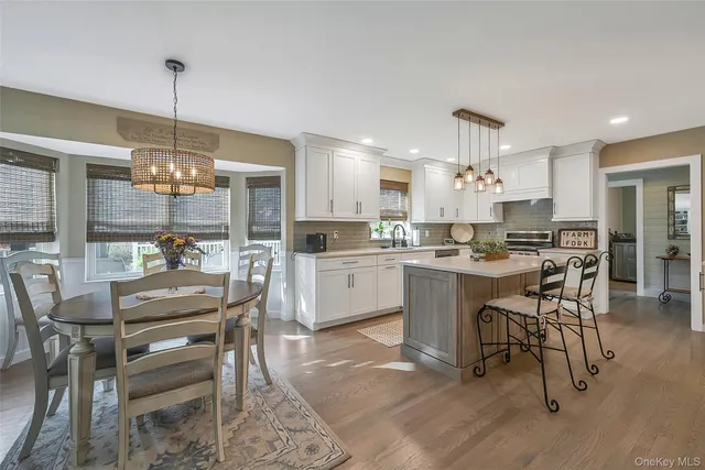 a kitchen with kitchen island a dining table chairs and white cabinets
