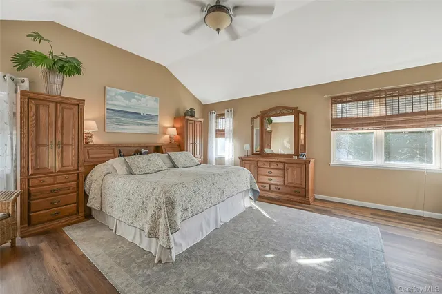 a bedroom with a bed and dresser with wooden floor