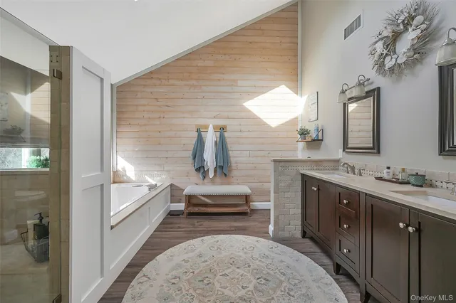 a spacious bathroom with a double vanity sink a mirror and a bathtub