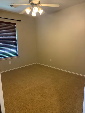 a view of an empty room with a chandelier fan