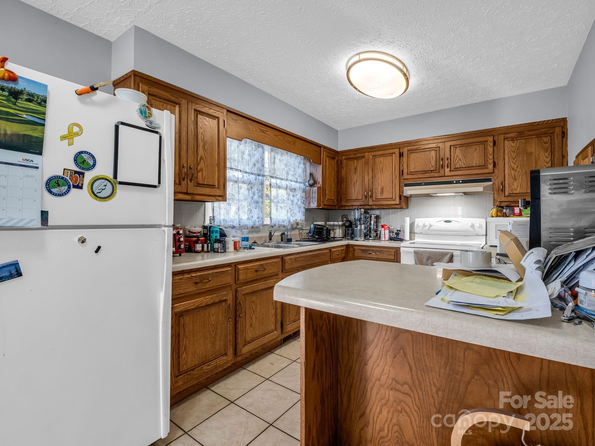 290 Stepp Mill Road Hendersonville, NC 28792 - Photo 9 of 29 a kitchen with a refrigerator a stove a sink a chimney and furniture