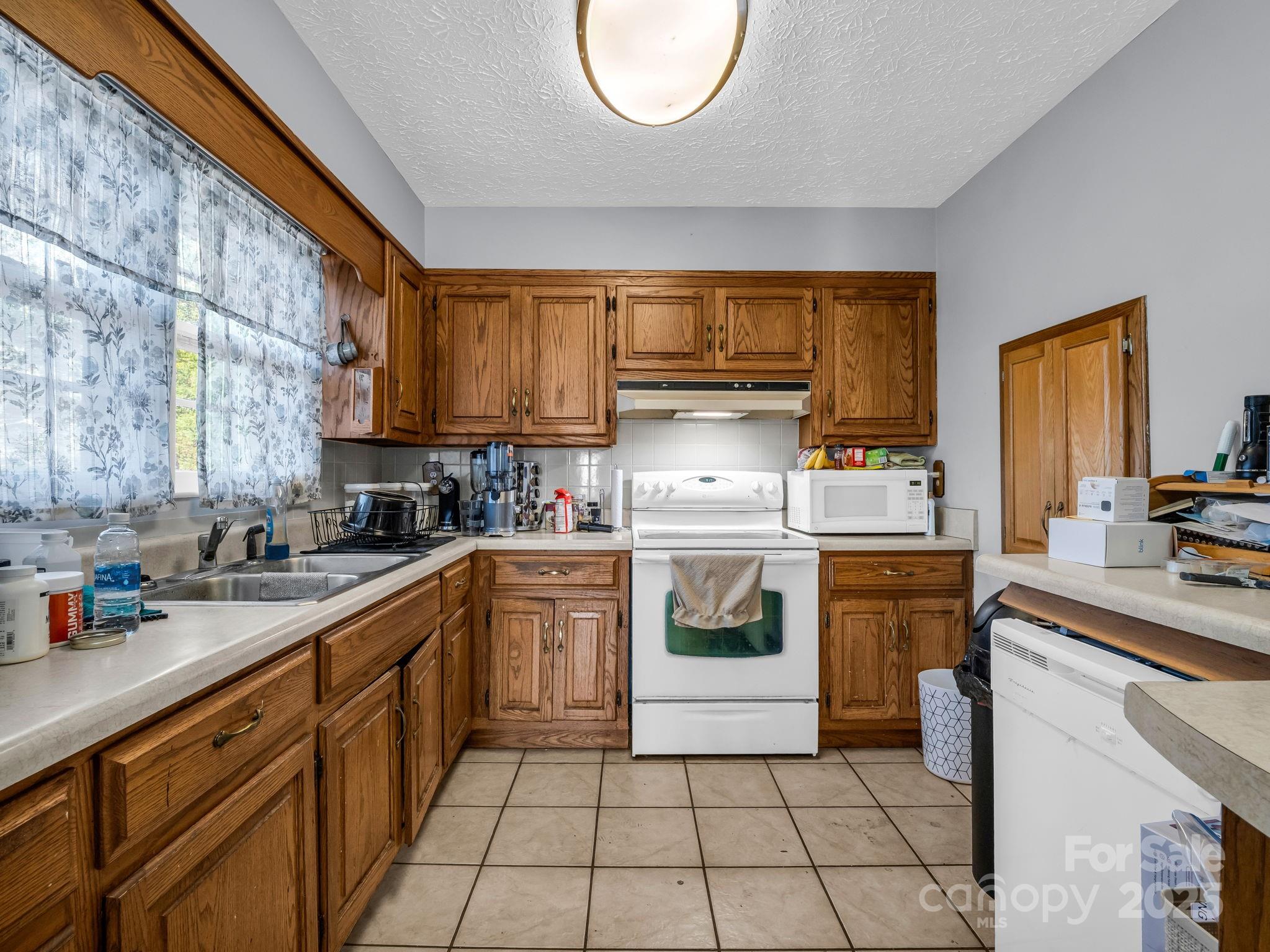 290 Stepp Mill Road Hendersonville, NC 28792 - Photo 10 of 29 a kitchen with a sink a stove a microwave and cabinets