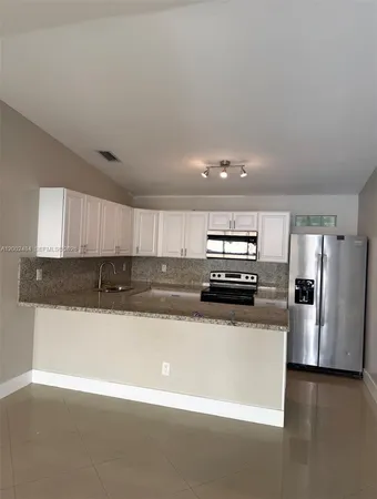 a kitchen with stainless steel appliances granite countertop a sink and a refrigerator
