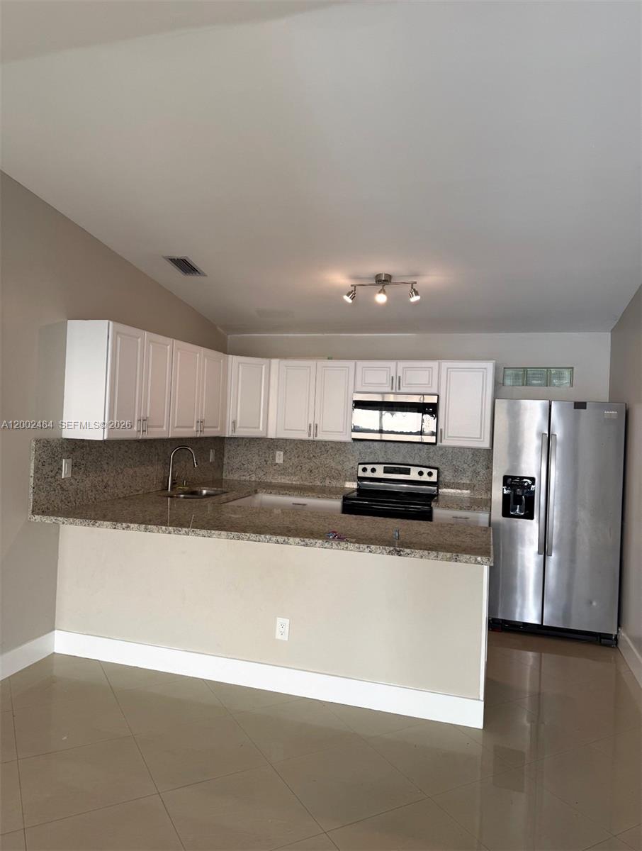 a kitchen with stainless steel appliances granite countertop a sink and a refrigerator