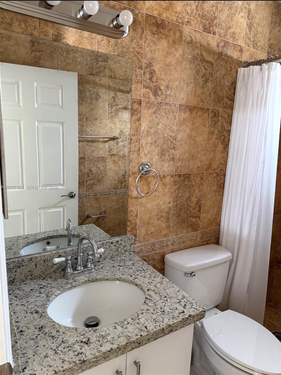 17501 Southwest 142nd Court Miami, FL 33177 - Photo 6 of 10 a bathroom with a granite countertop toilet a sink and mirror