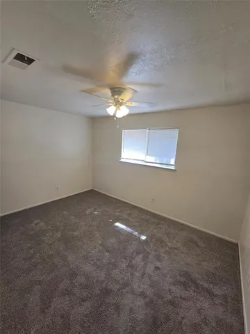 an empty room with a chandelier fan and windows