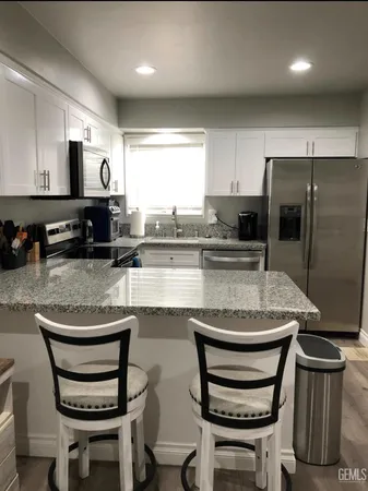 a kitchen with stainless steel appliances granite countertop a stove a refrigerator a sink a dining table and chairs