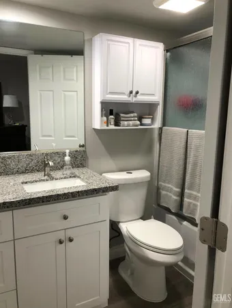 a bathroom with a granite countertop toilet sink and mirror