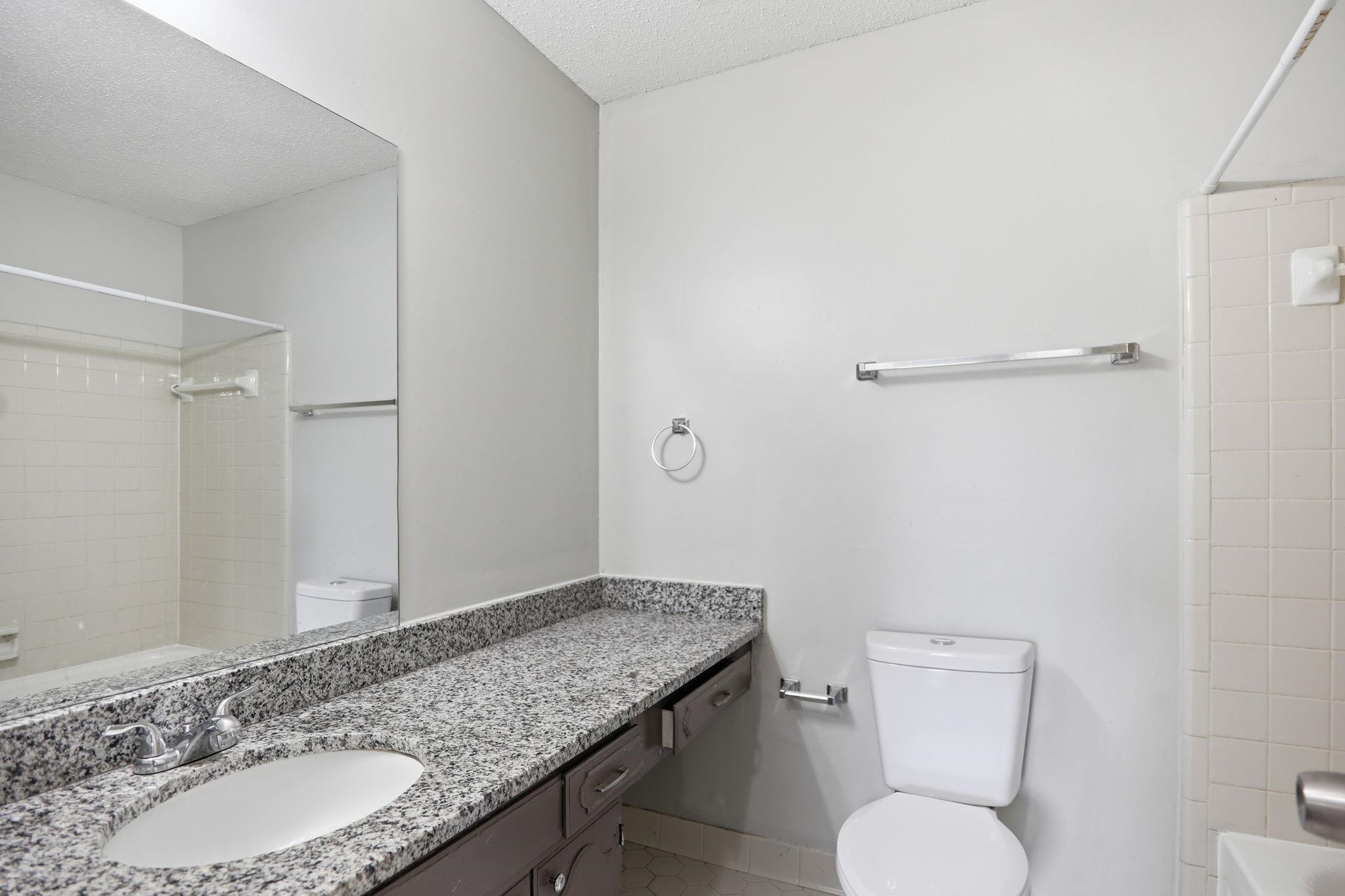 3113 Raleigh Ridge Cove Memphis, TN 38128 - Photo 32 of 38 Bathroom featuring a granite countertop vanity with an integrated sink, a large wall-mounted mirror, a commode, and a shower with white tile surround