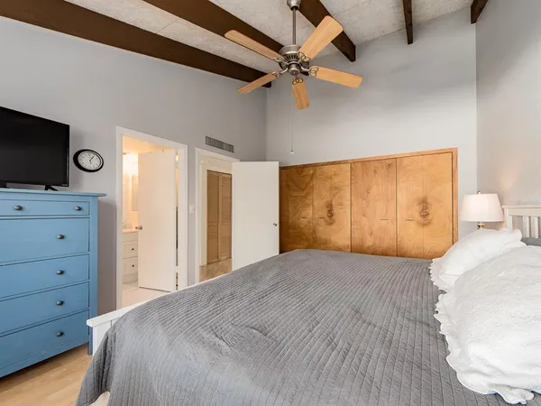 a bedroom with a large bed and a flat tv screen on dresser