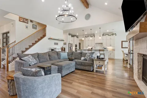 a living room with furniture kitchen view and a chandelier