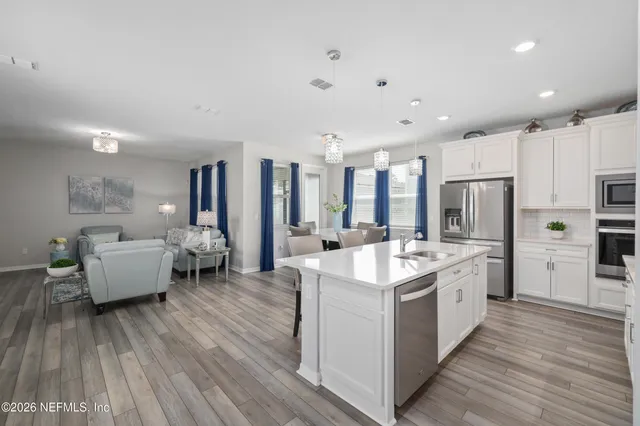 a large kitchen with kitchen island a sink white cabinets and stainless steel appliances