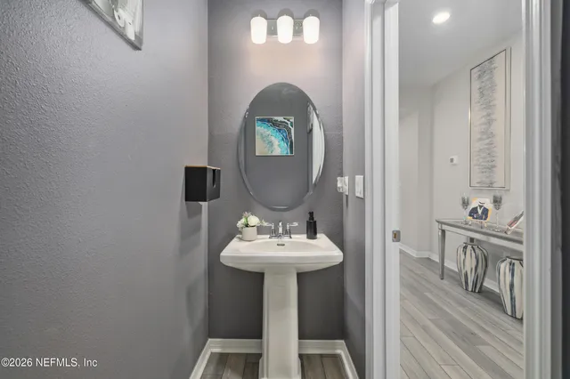 a large white kitchen with a stove a refrigerator a sink dishwasher a dining table and chairs with wooden floor