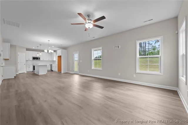 a view of an empty room with a window and a kitchen