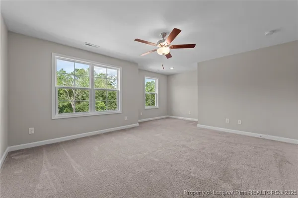 an empty room with windows and ceiling fan view