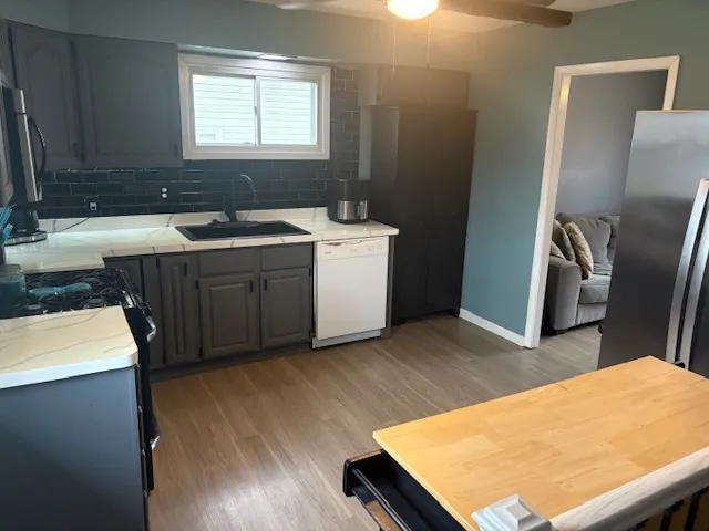 a kitchen with a sink appliances and wooden floor