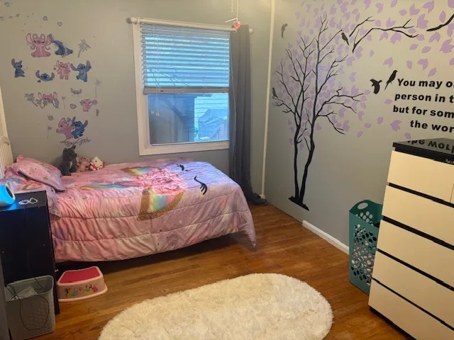 a bedroom with a bed and a window with wooden floor