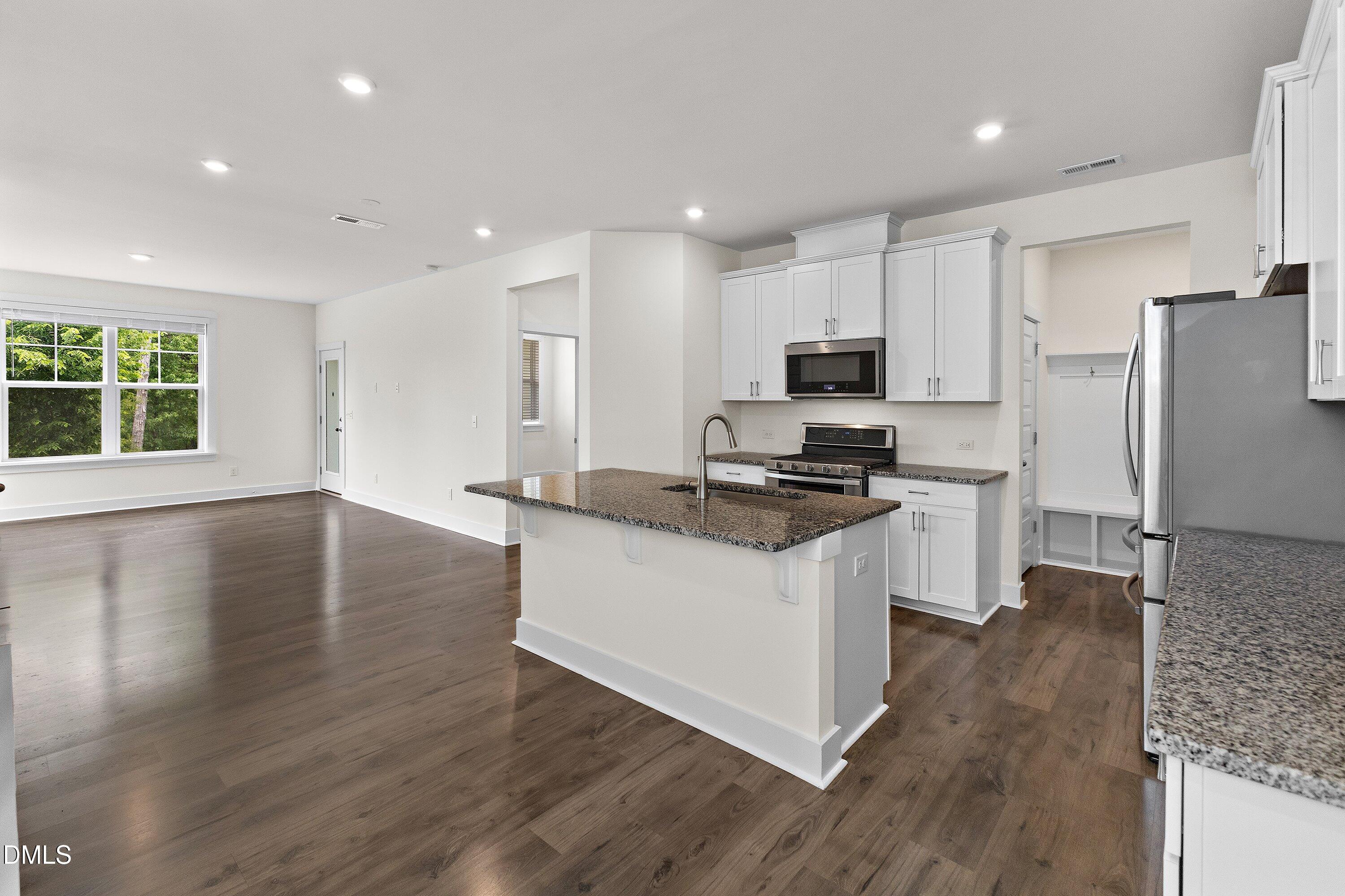 156 Sears Ridge Lane Morrisville, NC 27560 - Photo 5 of 49 a kitchen with stainless steel appliances granite countertop a stove a sink a refrigerator and white cabinets with wooden floor