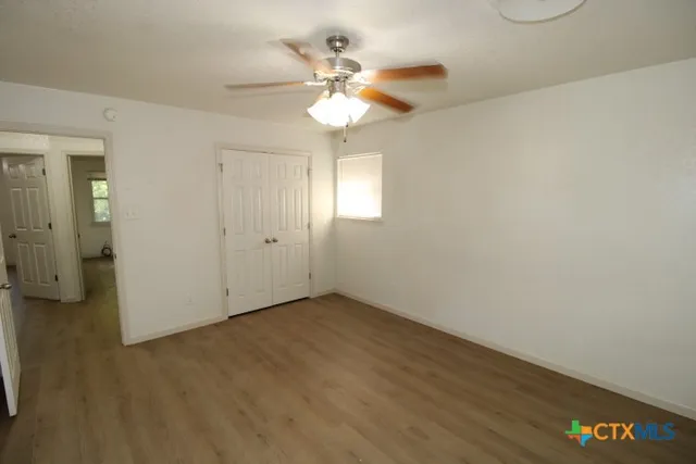 an empty room with a chandelier fan and windows