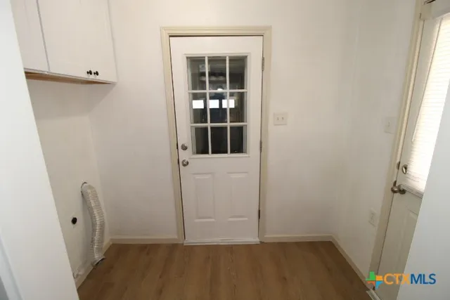 an empty room with wooden floor and entrance