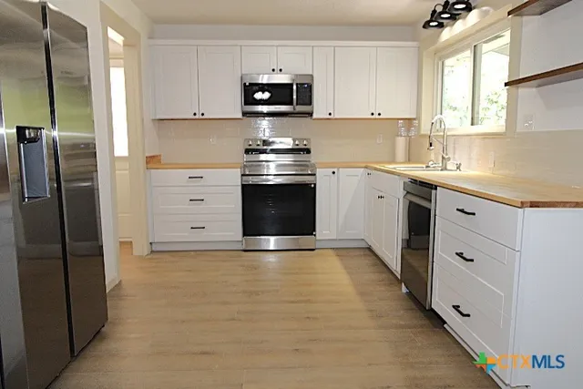 a kitchen with granite countertop a refrigerator stove and sink