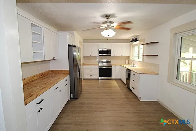 a large kitchen with cabinets wooden floor and stainless steel appliances