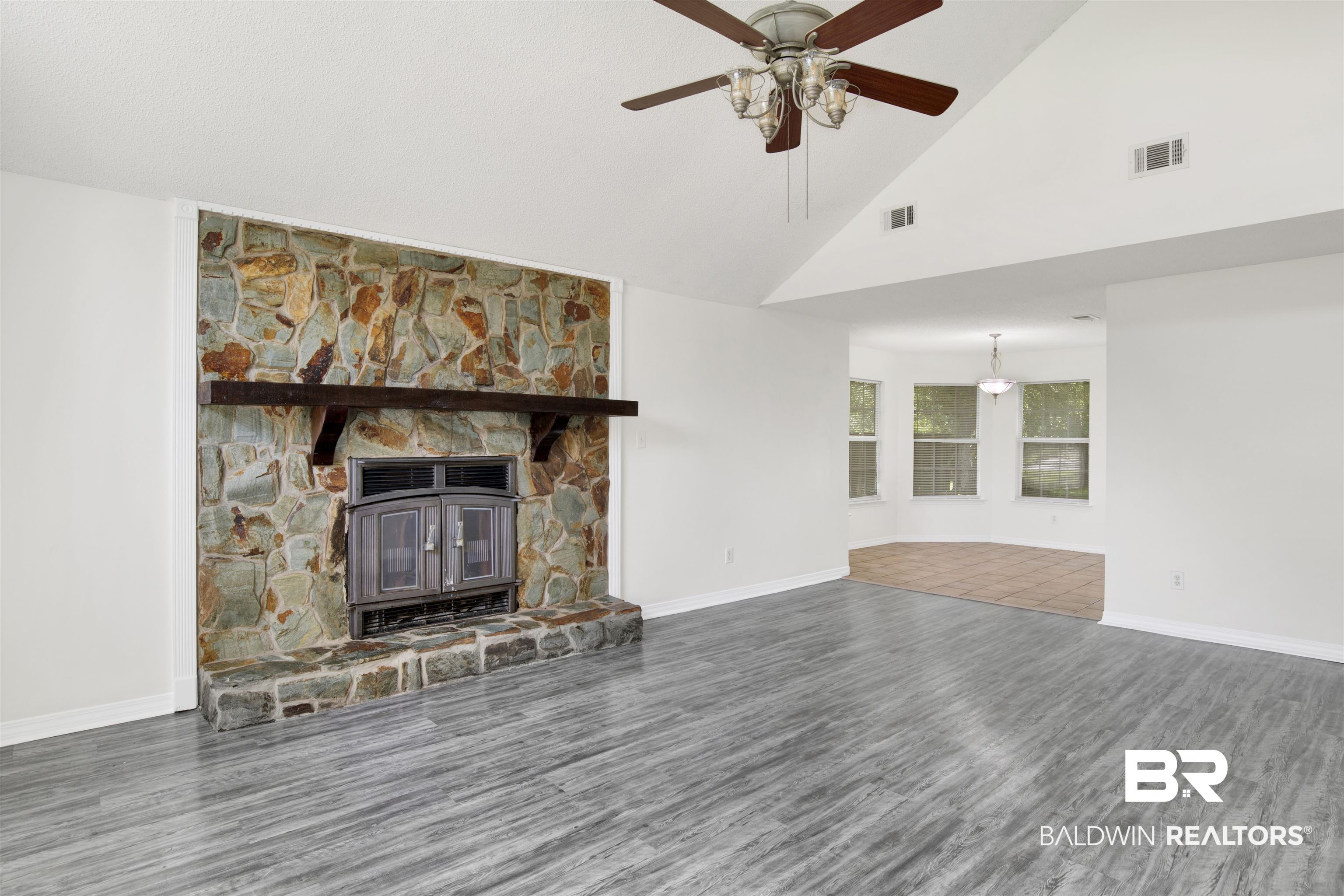 5480 Country Club Boulevard Theodore, AL 36582 - Photo 3 of 36 Unfurnished living room featuring high vaulted ceiling, wood-type flooring, ceiling fan, and a stone fireplace