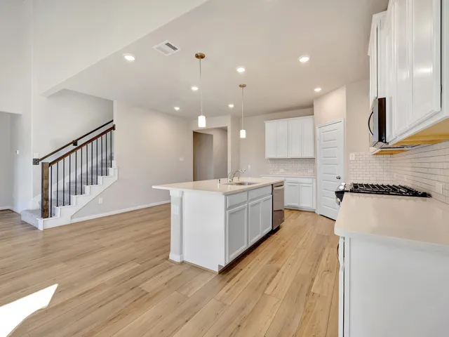 a large white kitchen with kitchen island a sink a counter top and stainless steel appliances