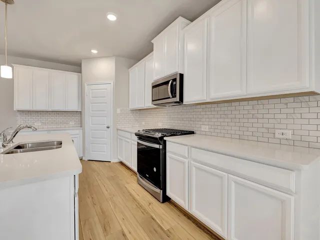 a kitchen with granite countertop a sink a stove and cabinets