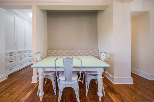 a large white kitchen with kitchen island a sink dishwasher a stove a dining table and chairs with wooden floor